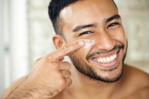 men is applying face cream on his face 