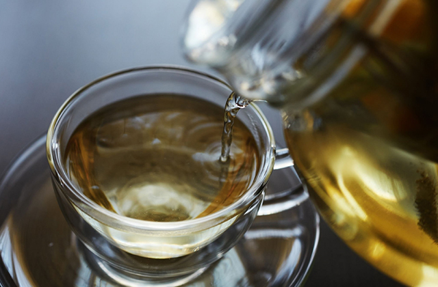 Green tea is being poured into the cup